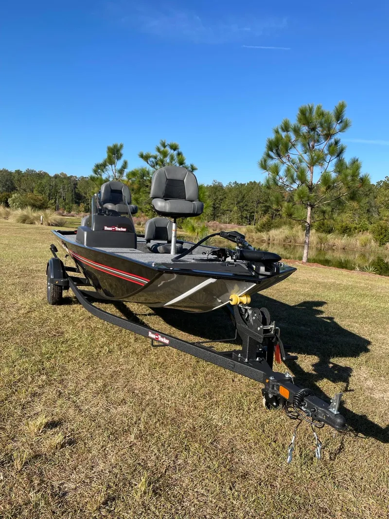 Slide: The Image of 2025 Tracker Bass Tracker Classic XL boat on grassy field under clear blue sky. - 2