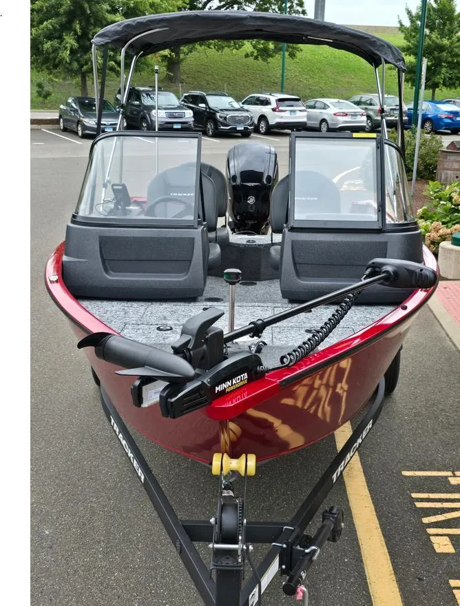 Slide: The Image of 2025 Tracker Pro Guide V-16 WT boat in parking lot, red exterior, equipped with Minn Kota motor. - 2