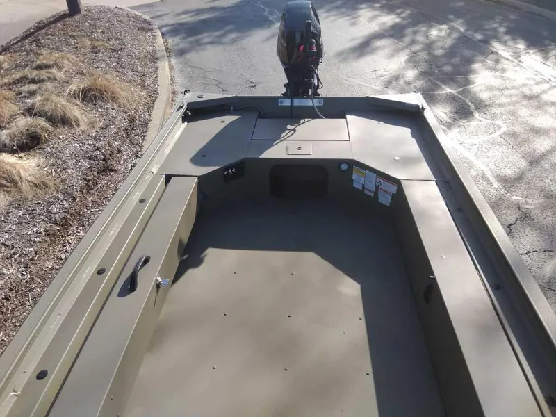 Slide: The Image of 2025 Tracker Grizzly 1654 T Sportsman boat, empty deck view, parked on pavement. - 40