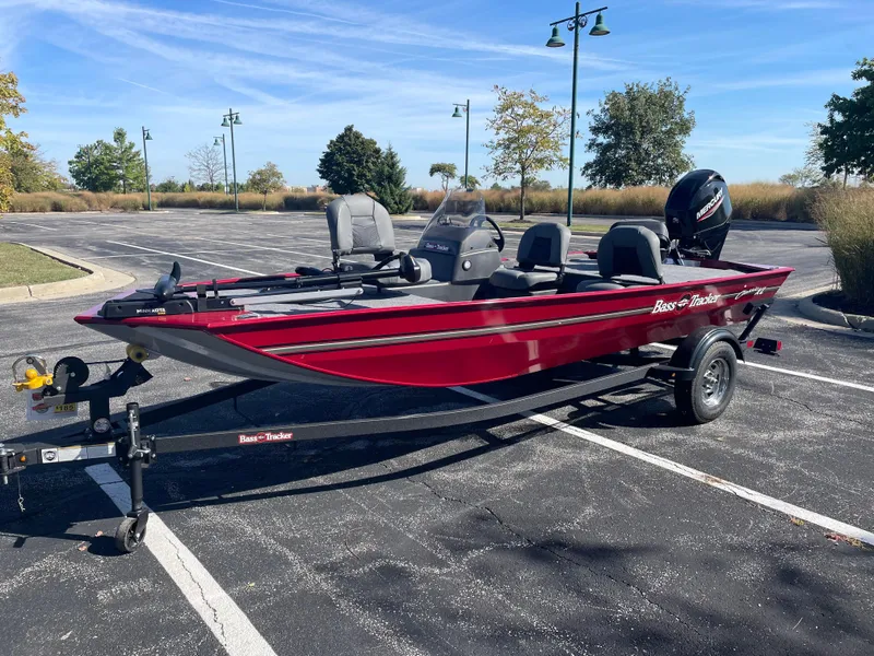 Slide: The Image of 2025 Tracker Bass Tracker Classic XL boat in a parking lot, red exterior, on a trailer. - 2