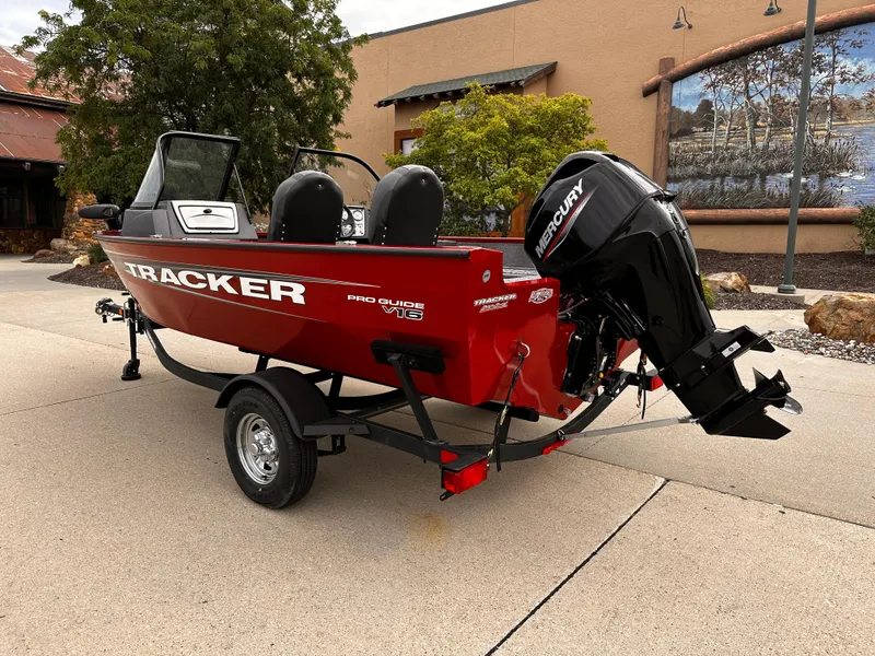 Slide: The Image of 2025 Tracker Pro Guide V-16 WT boat with Mercury outboard engine, parked outdoors. - 2