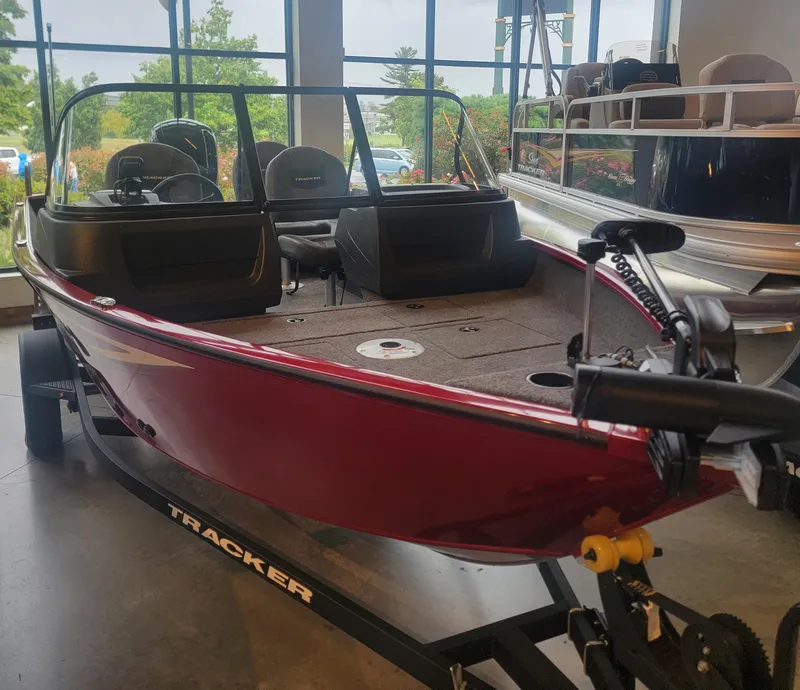Slide: The Image of 2025 Tracker Pro Guide V-16 WT boat in showroom, red exterior, on trailer. - 5