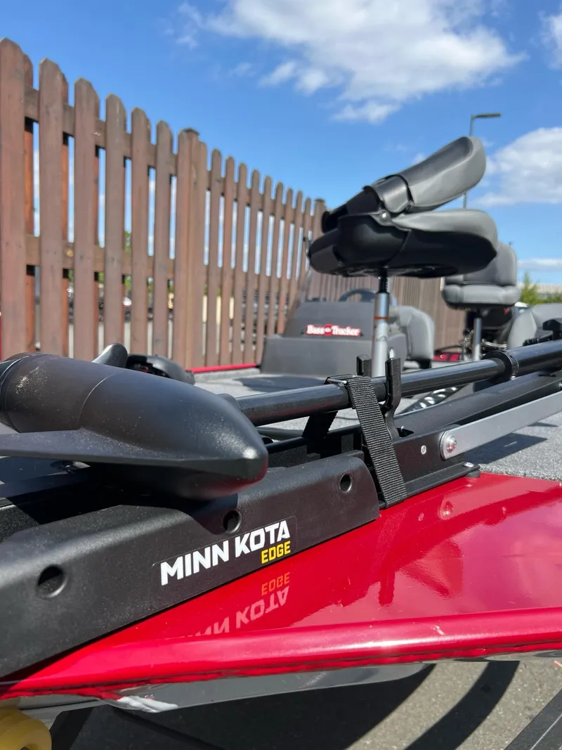 Slide: The Image of 2025 Tracker Bass Tracker Classic XL with Minn Kota Edge motor, red exterior, outdoor setting. - 3