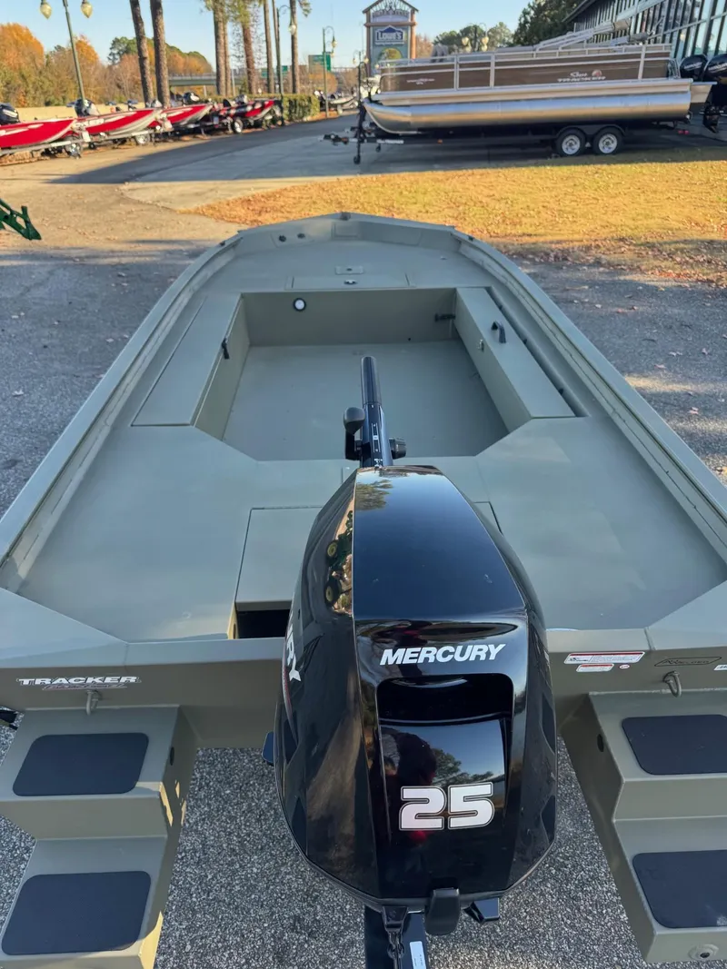 Slide: The Image of 2025 Tracker Grizzly 1654 T Sportsman boat with Mercury 25 engine, parked outdoors. - 45