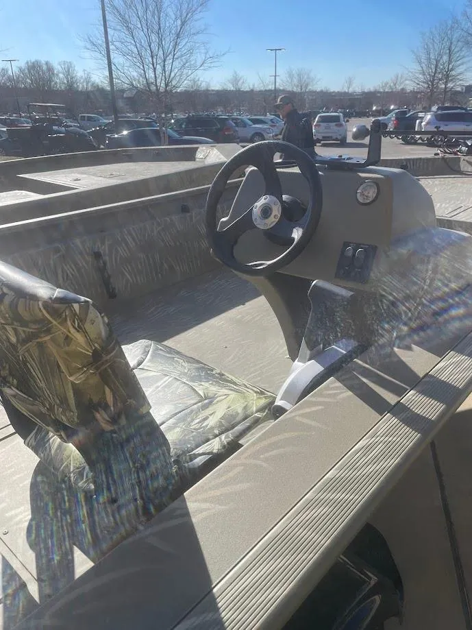 Slide: The Image of 2025 Tracker Grizzly 1754 SC boat interior with steering wheel and camo seat. - 2