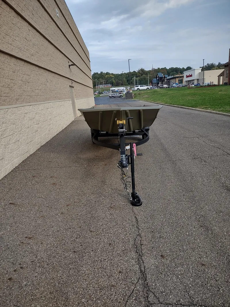 Slide: The Image of 2025 Tracker Grizzly 1754 Jon boat on trailer, parked beside a building. - 2