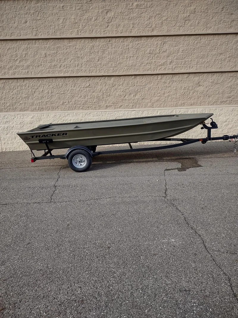 Slide: The Image of 2025 Tracker Grizzly 1754 Jon boat on trailer, parked against a beige wall. - 3