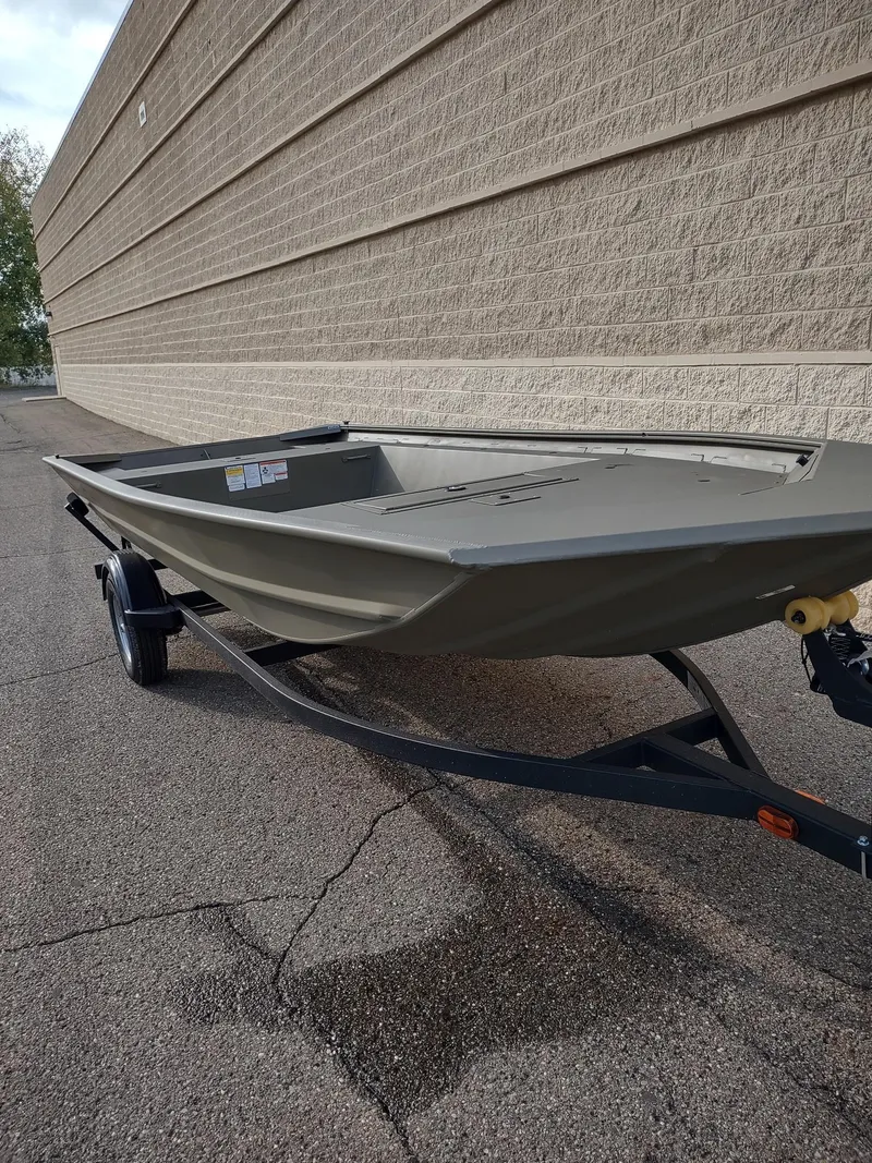 Slide: The Image of 2025 Tracker Grizzly 1754 Jon boat on trailer, parked beside a brick wall. - 4
