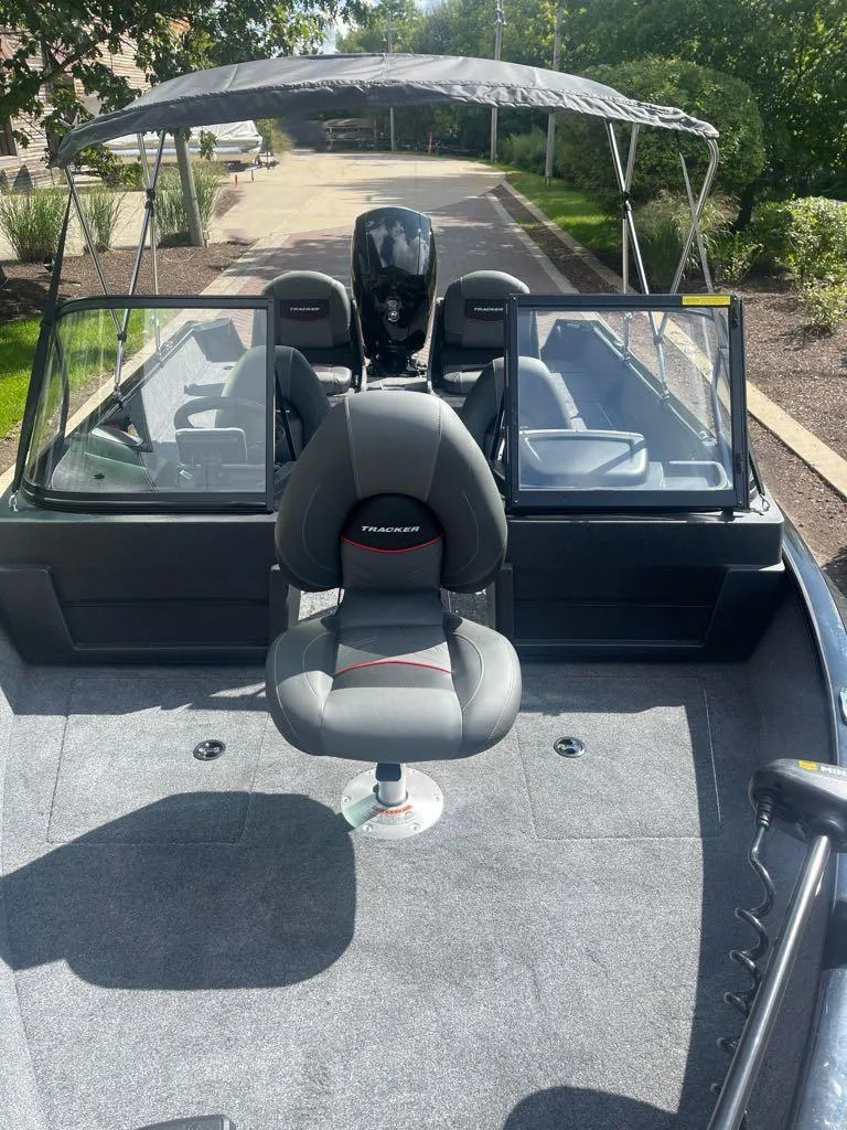 Slide: The Image of 2025 Tracker Pro Guide V-175 Combo boat with seating and canopy, parked outdoors. - 2