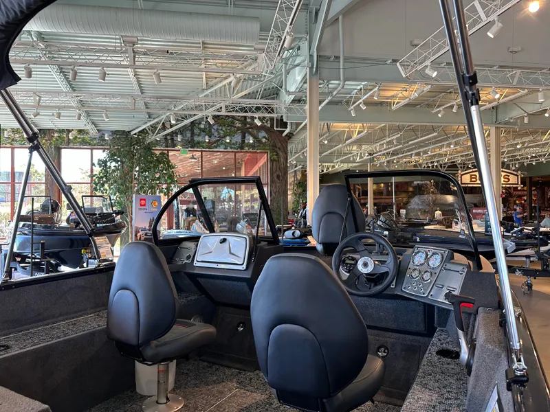 Slide: The Image of 2025 Tracker Pro Guide V-175 Combo boat interior in showroom, featuring modern seating and controls. - 2