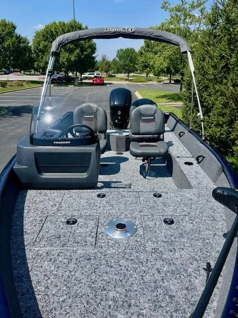 Slide: The Image of 2025 Tracker Pro Guide V-16 SC boat with seating and steering console, parked outdoors. - 4