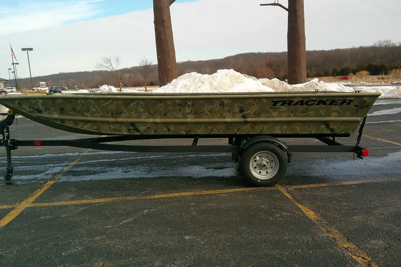 Slide: The Image of 2025 Tracker Grizzly 1648 Jon boat on trailer in snowy parking lot. - 2