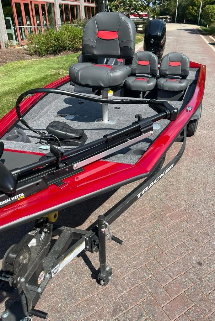 Slide: The Image of 2025 Tracker Pro Team 175 Crappie Edition boat, red with gray seating, parked outdoors. - 2