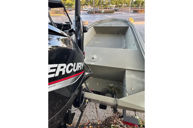 Slide: The Image of 2025 Tracker Grizzly 1648 Jon boat with Mercury engine in a parking lot. - 3
