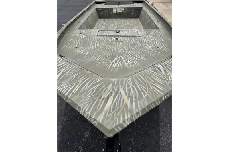 Slide: The Image of 2025 Tracker Grizzly 1754 Jon boat with camouflage pattern on a paved surface. - 2