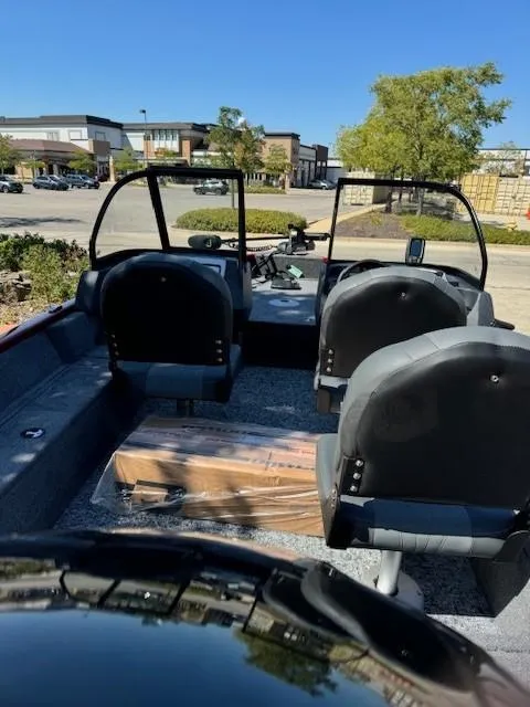 Slide: The Image of 2025 Tracker Pro Guide V-16 WT boat interior with seating and windshield, parked outdoors. - 2
