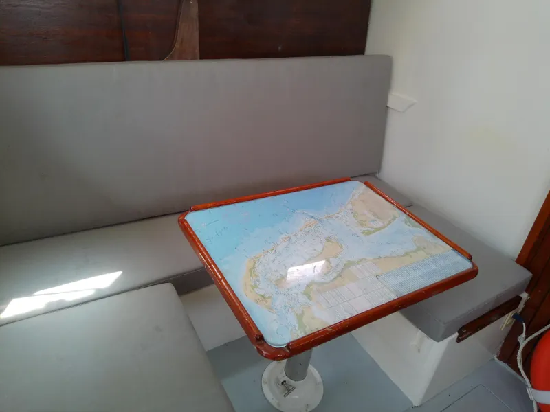 Slide: The Image of 1978 Downeast 38 interior with map-covered table and gray seating. - 26
