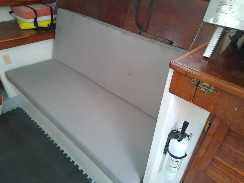 Slide: The Image of 1978 Downeast 38 interior with gray cushioned bench and wooden cabinetry. - 28