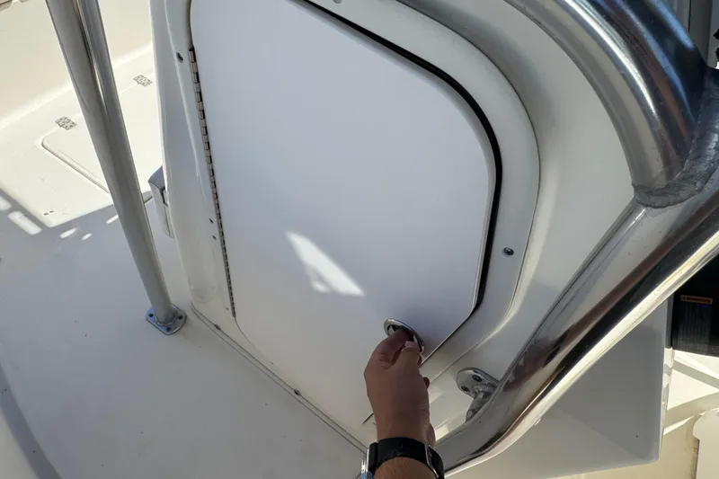 Slide: The Image of Hand opening storage compartment on 2019 Bulls Bay 230 Center Console boat. - 14
