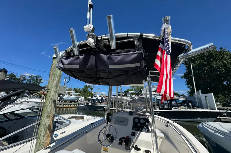 Slide: The Image of 2019 Bulls Bay 230 Center Console boat with American flag, docked under clear blue sky. - 7