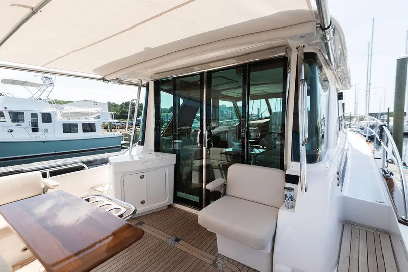 Slide: The Image of 2025 Sabre 43 Salon Express yacht with elegant outdoor seating and glass doors. - 13