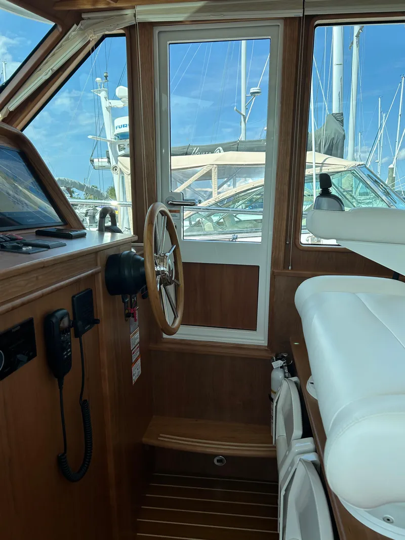 Slide: The Image of Interior of 2025 Sabre 43 Salon Express yacht with wooden steering wheel and white seating. - 27