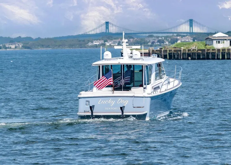 Slide: The Image of Sabre 43 Salon Express 2025 cruising with American flag, bridge in background. - 3