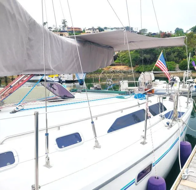 Slide: The Image of 1995 Catalina 36 Mk II sailboat docked with American flag, covered sail, and scenic background. - 37