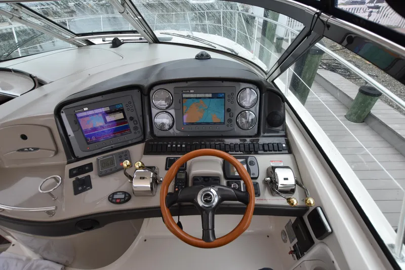 Slide: The Image of Cockpit of 2005 Sea Ray 420 Sundancer with navigation screens and wooden steering wheel. - 18