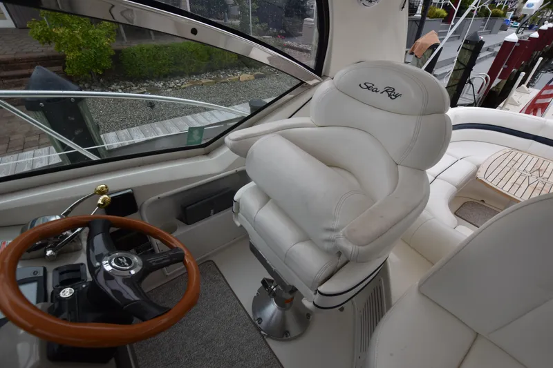 Slide: The Image of Captain's seat and helm of 2005 Sea Ray 420 Sundancer yacht, featuring luxurious white upholstery. - 19