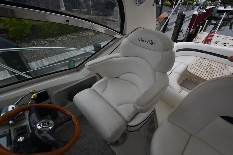 Slide: The Image of 2005 Sea Ray 420 Sundancer helm with white leather seat and wooden steering wheel. - 20