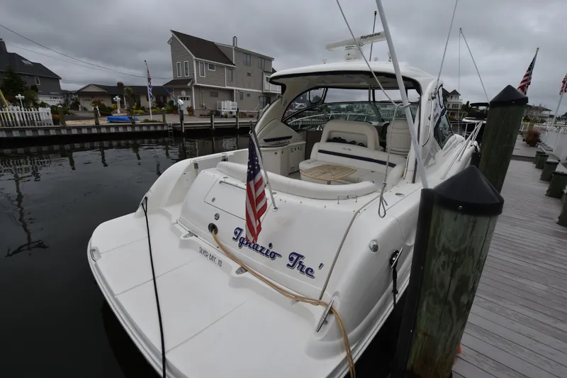 Slide: The Image of 2005 Sea Ray 420 Sundancer docked, featuring a spacious deck and American flag. - 43