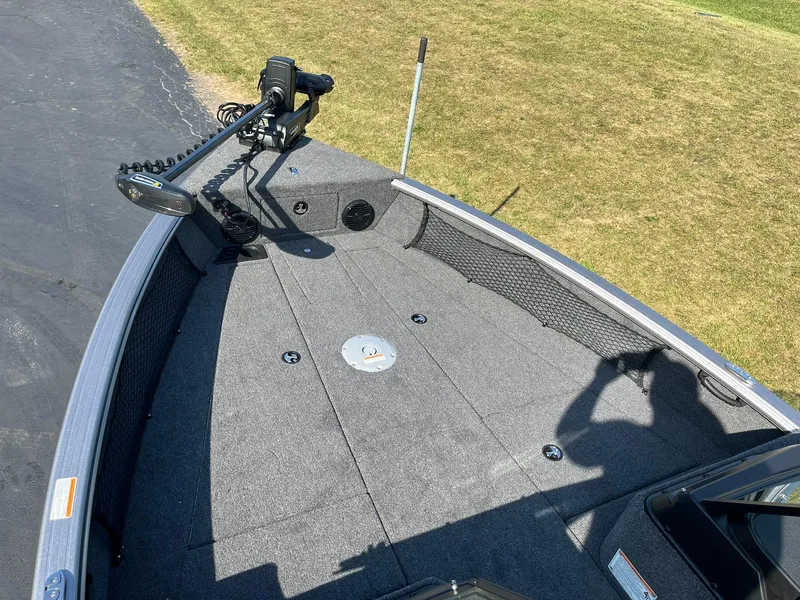 Slide: The Image of 2025 Lund 2075 Impact XS Sport boat deck with trolling motor, parked on pavement. - 15