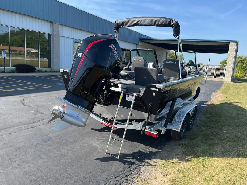 Slide: The Image of 2025 Lund 2075 Impact XS Sport boat on trailer, parked outdoors. - 2