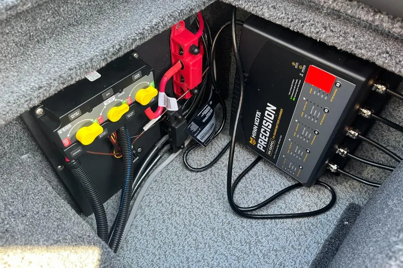 Slide: The Image of 2025 Lund 2075 Impact XS Sport boat battery compartment with precision charger and wiring. - 29
