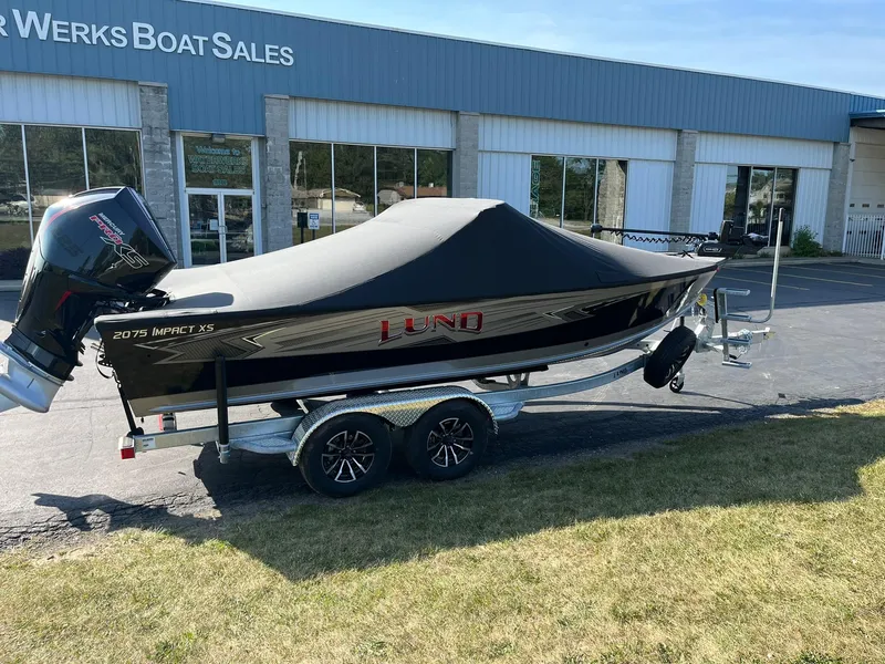 Slide: The Image of 2025 Lund 2075 Impact XS Sport boat on trailer outside dealership. - 31