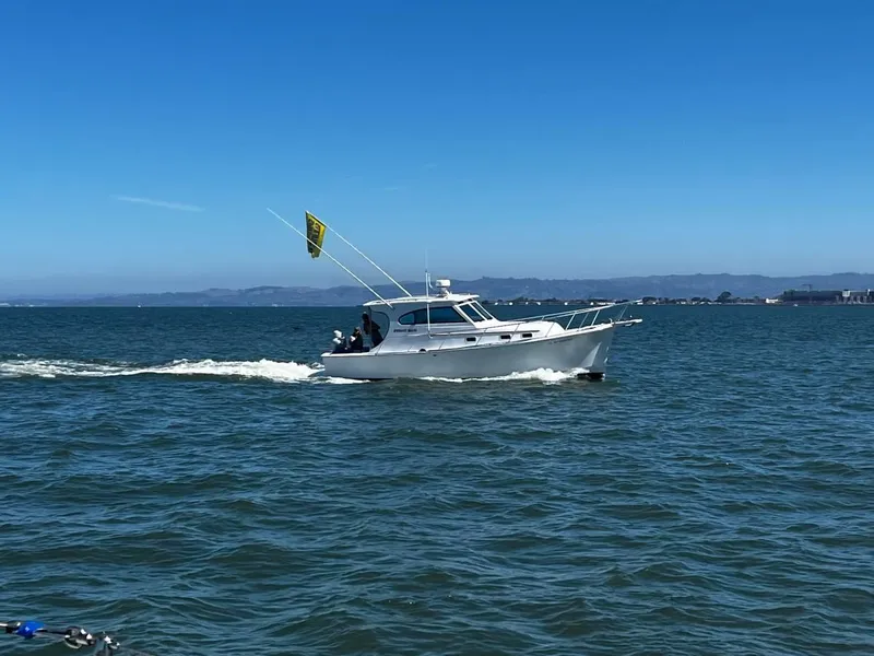 Slide: The Image of 1999 Mainship 30 boat cruising on open water under clear blue sky. - 12