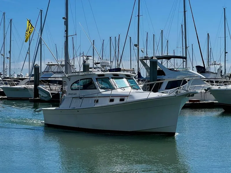 Slide: The Image of 1999 Mainship 30 boat docked in a marina with sailboats in the background. - 14