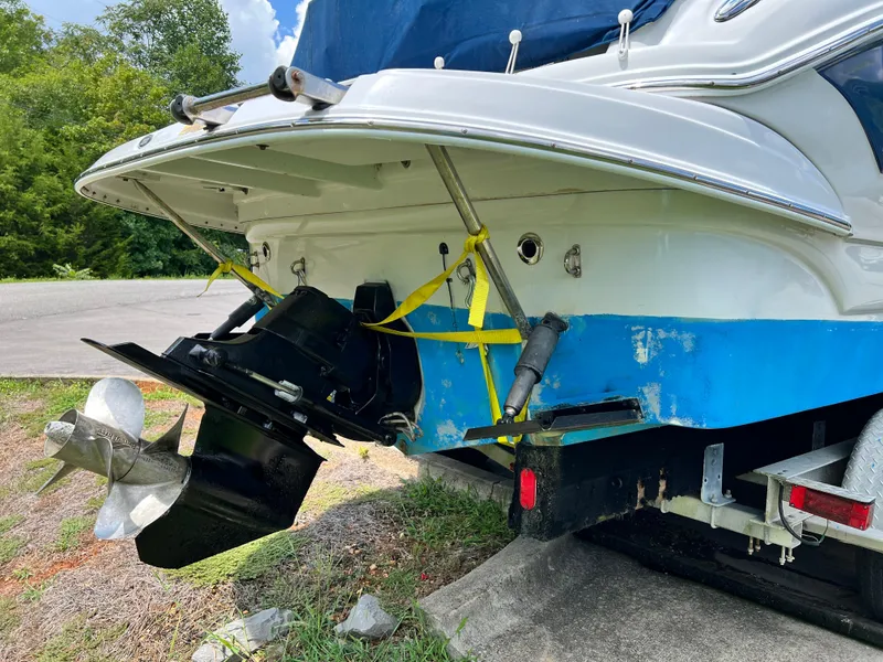 Slide: The Image of 2006 Crownline 250cr boat stern with propeller and trailer, parked on grass. - 1