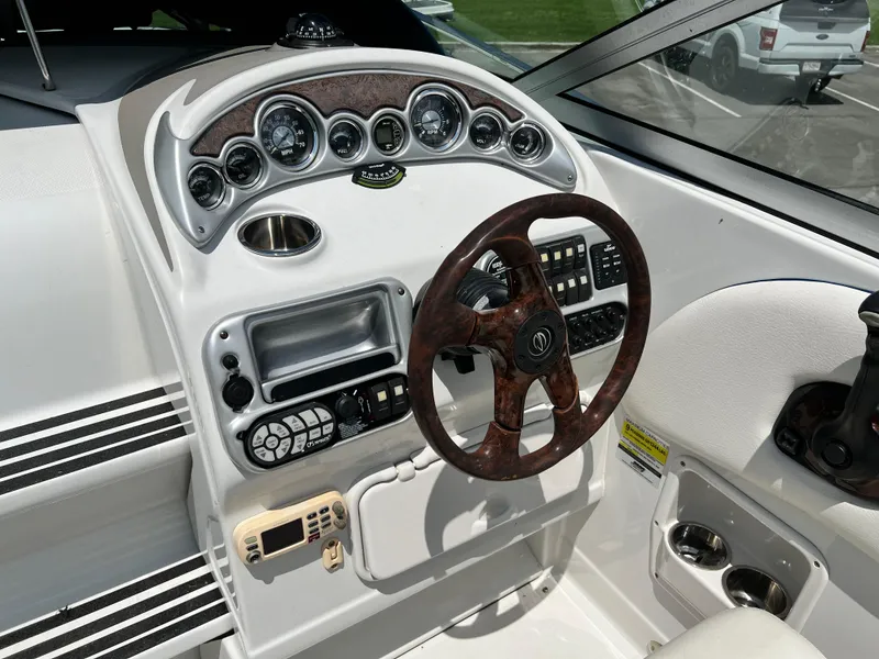 Slide: The Image of 2006 Crownline 250CR boat dashboard with wood-grain steering wheel and instrument panel. - 2