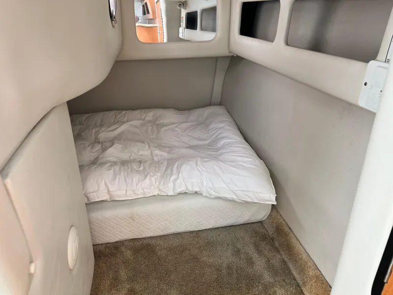 Slide: The Image of 2006 Crownline 250cr cabin interior with bed, white bedding, and carpeted floor. - 8