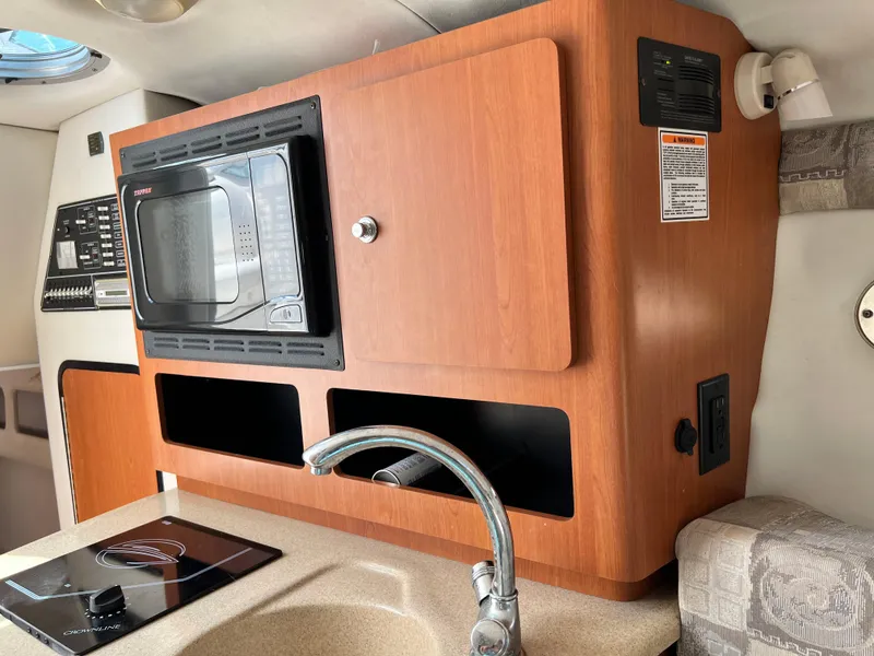 Slide: The Image of 2006 Crownline 250CR boat interior with microwave, stove, and sink in kitchenette area. - 9
