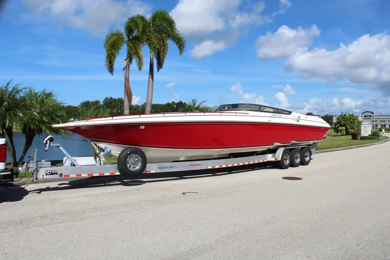 Slide: The Image of Red 2007 Fountain 42 Lightning boat on trailer, parked near palm trees. - 0