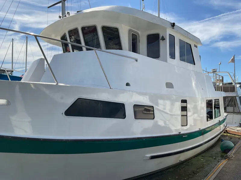 The Image of White 1998 Sunnfjord Custom boat docked, featuring a green stripe and multiple windows. - 0