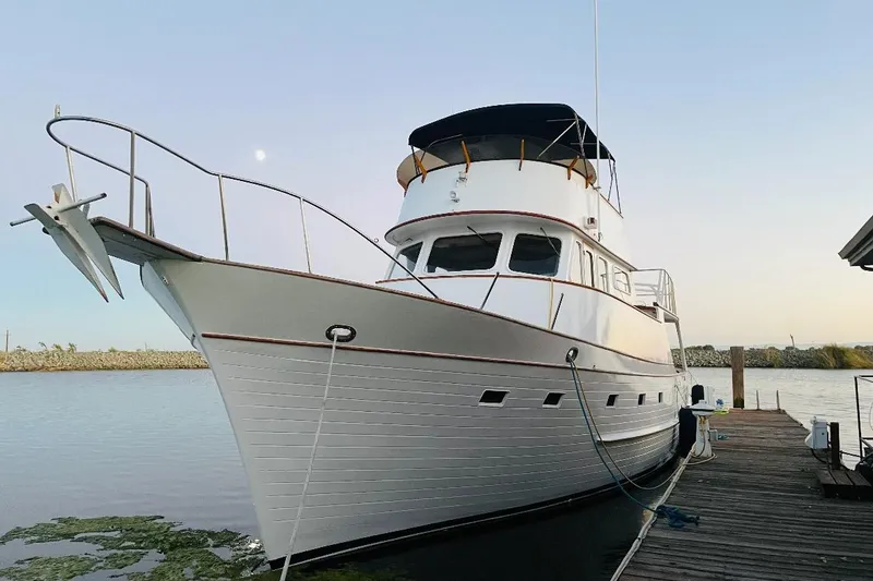 Slide: The Image of 1977 Grand Alaskan Raised Pilothouse yacht docked by the water. - 1