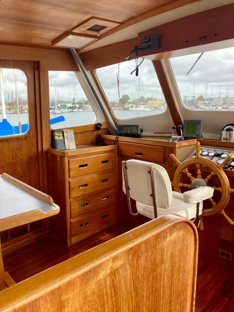 Slide: The Image of 1977 Grand Alaskan Raised Pilothouse interior with wooden helm and marina view. - 10