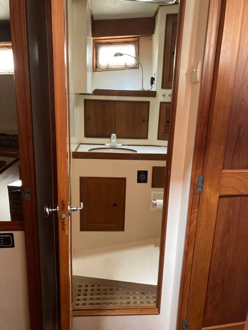 Slide: The Image of 1977 Grand Alaskan Raised Pilothouse bathroom with wooden cabinetry and mirror. - 12