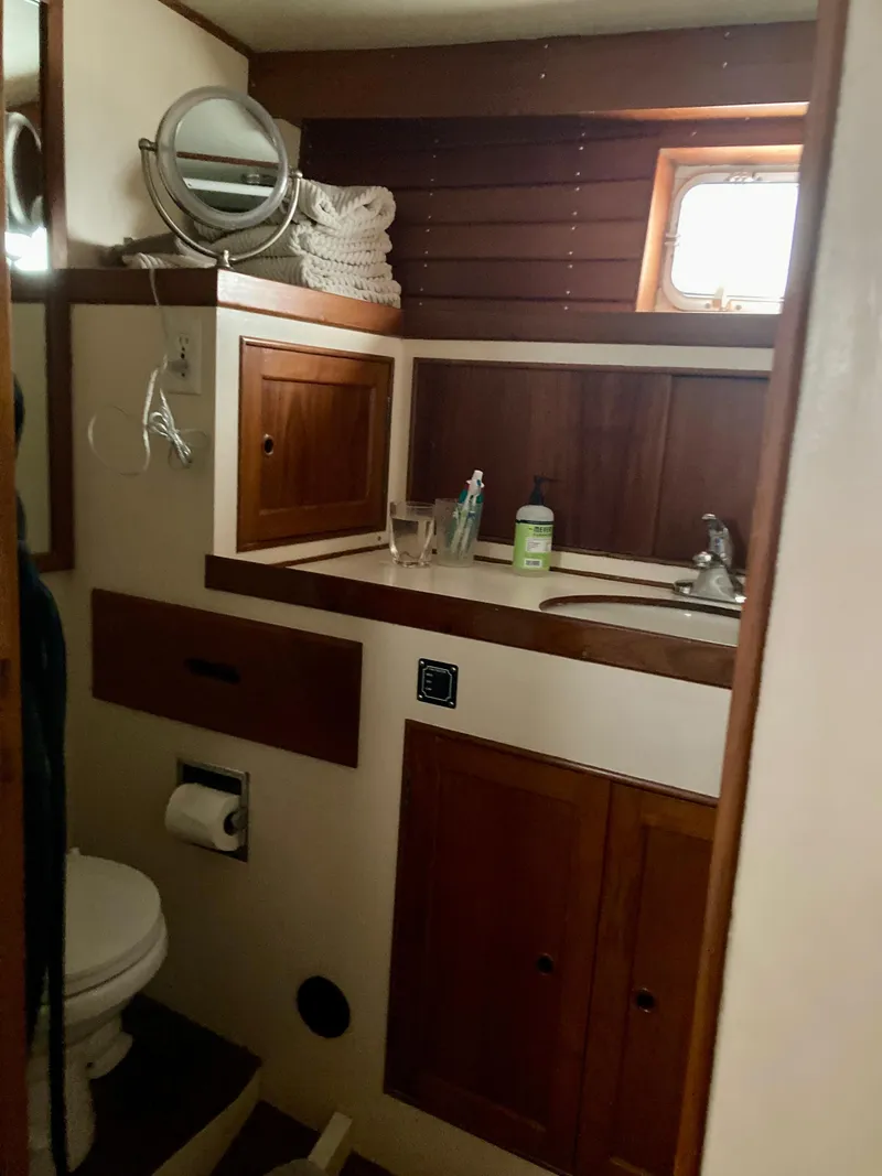 Slide: The Image of 1977 Grand Alaskan Raised Pilothouse bathroom with wooden cabinets and nautical decor. - 15