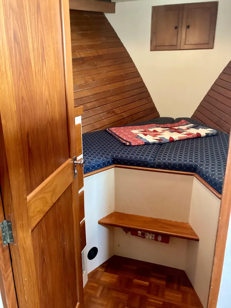 Slide: The Image of Cozy cabin interior of 1977 Grand Alaskan Raised Pilothouse with wooden accents and quilted bedding. - 17