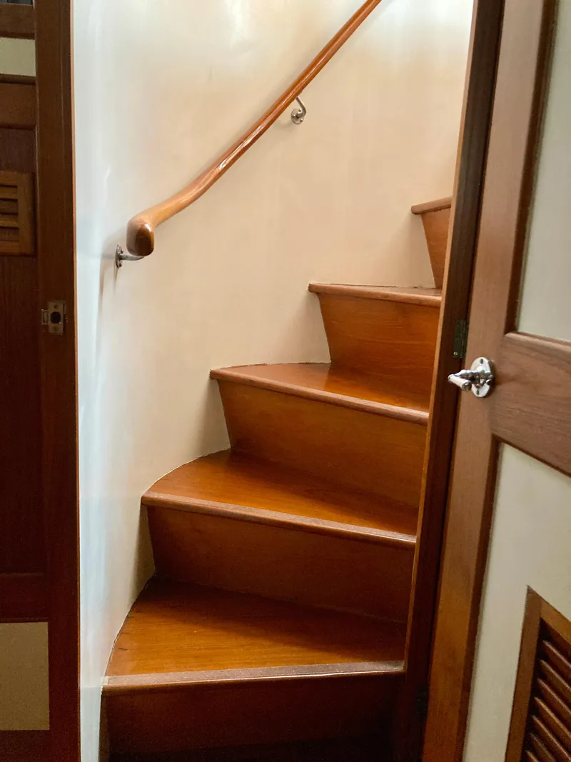 Slide: The Image of Wooden staircase inside 1977 Grand Alaskan Raised Pilothouse yacht, featuring elegant curved design. - 19